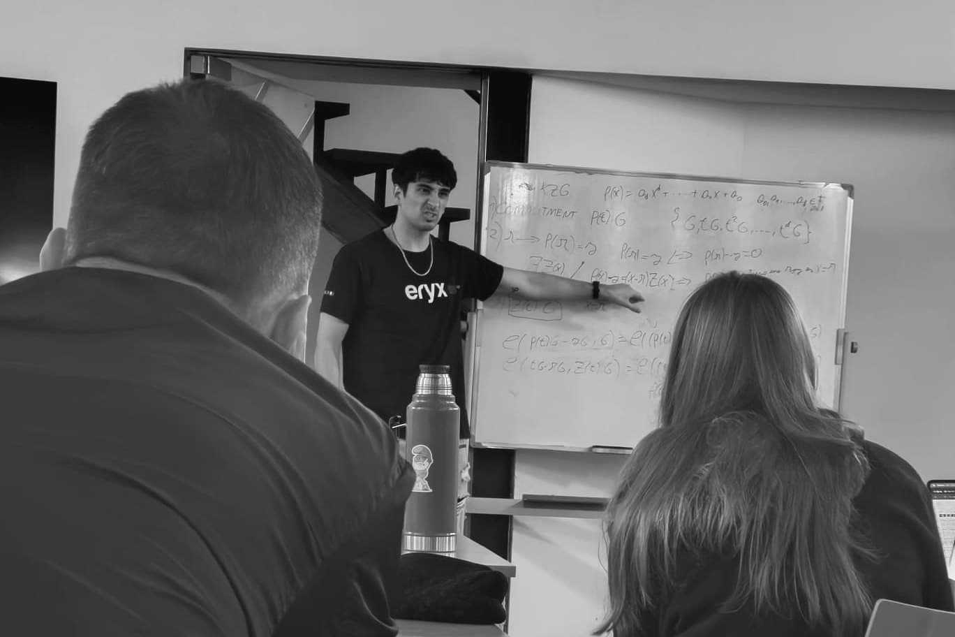 David at a whiteboard full of equations, teaching a small group.
